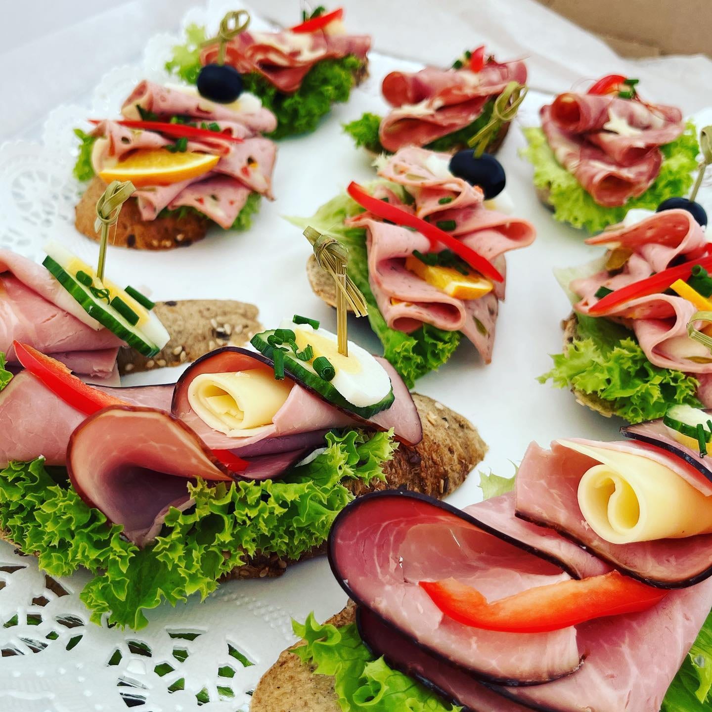 Platte mit garnierten Brötchen mit Schinken, Käse, Paprika und Oliven
