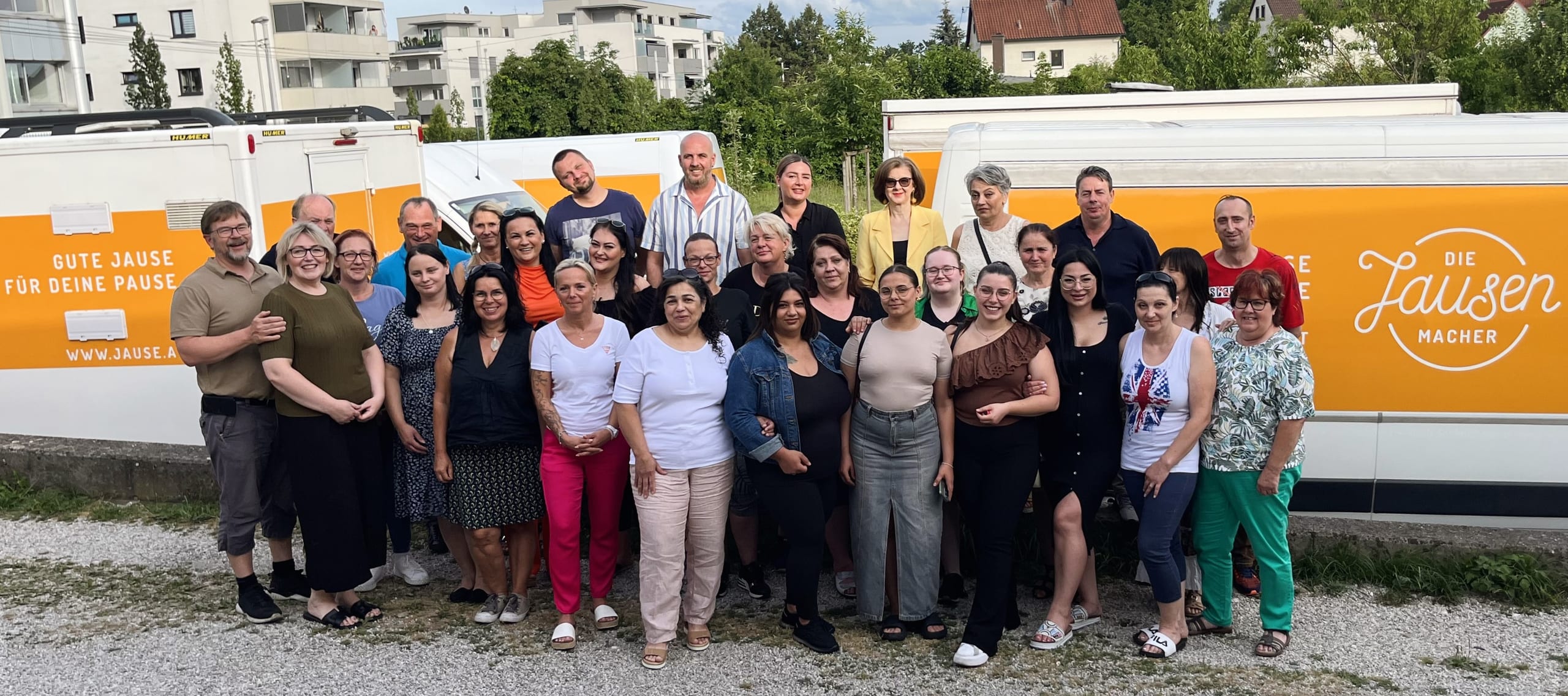 Das Jausenmacher-Team beim Sommerfest 2024 vor den orangen Jausenmobilen